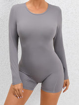 a woman in a grey bodysuit posing for the camera