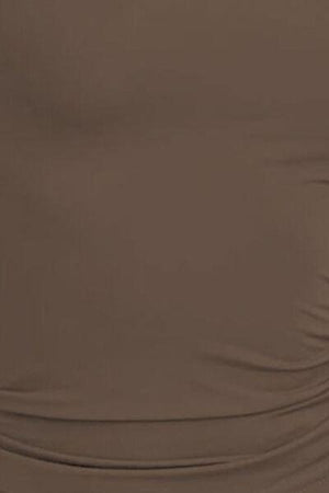 a woman wearing a brown top with a black belt