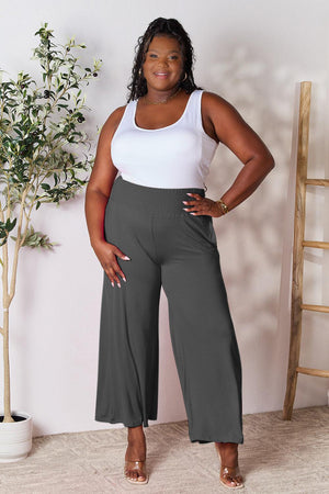 a woman in a white tank top and grey pants