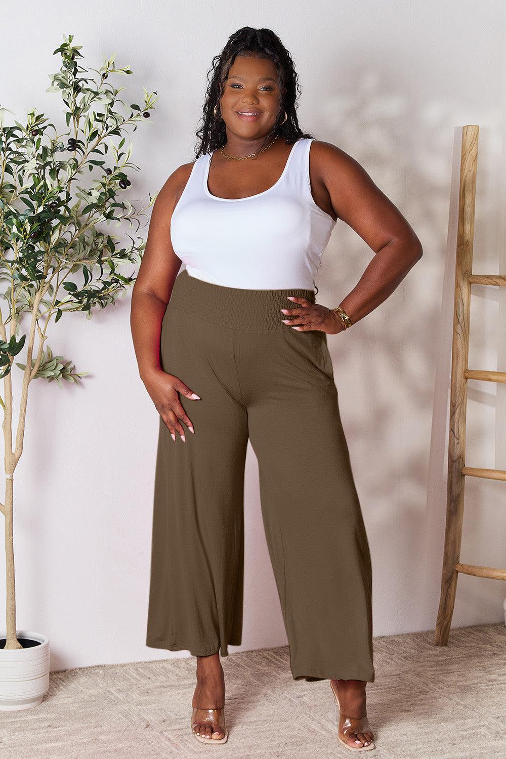 a woman in a white tank top and brown pants