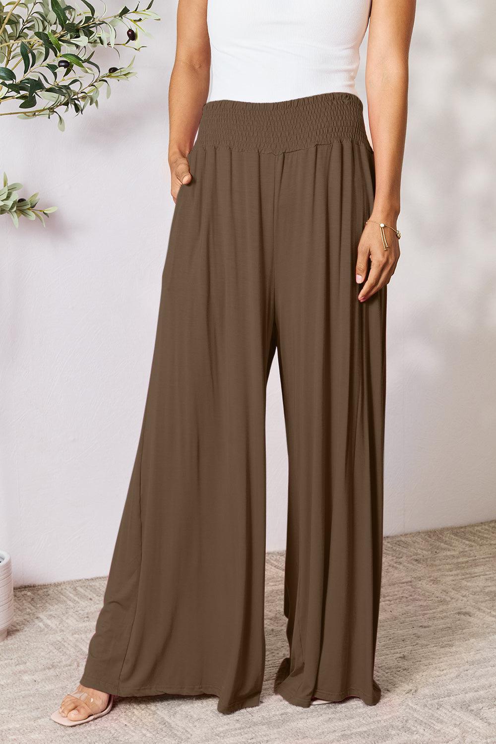 a woman in a white tank top and brown pants