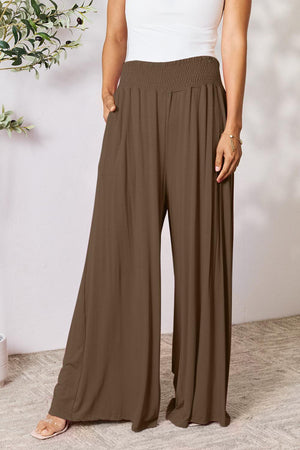 a woman in a white tank top and brown pants