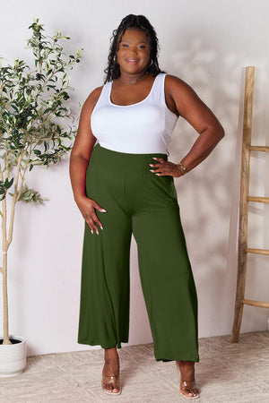 a woman in a white top and green pants
