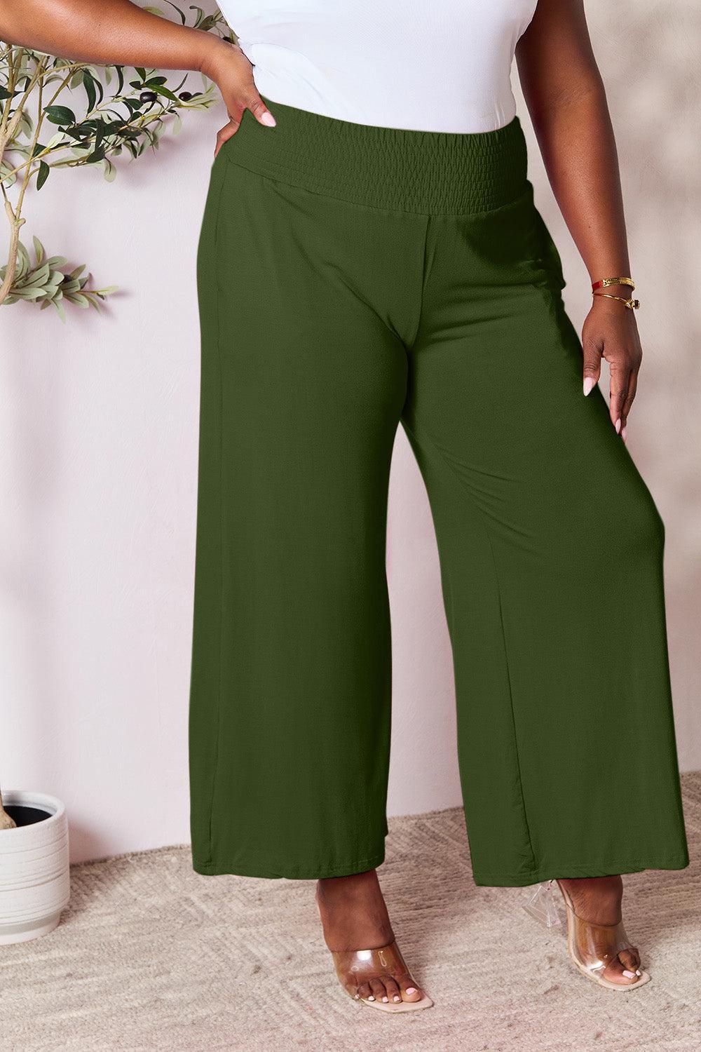 a woman in a white top and green pants