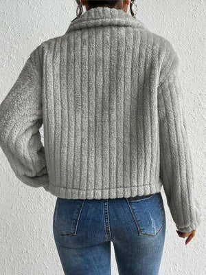 a woman wearing a gray sweater and jeans