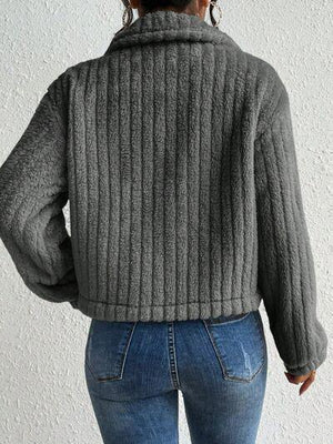 a woman wearing a gray sweater and jeans