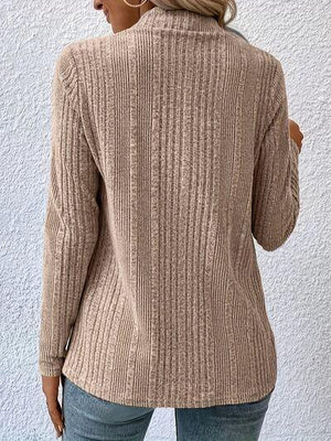 a woman wearing a tan sweater and jeans