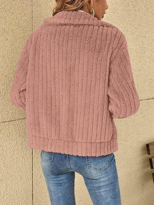 a woman wearing a pink sweater and jeans
