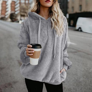 a woman in a gray hoodie holding a cup of coffee