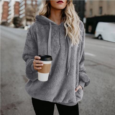 a woman in a gray hoodie holding a cup of coffee