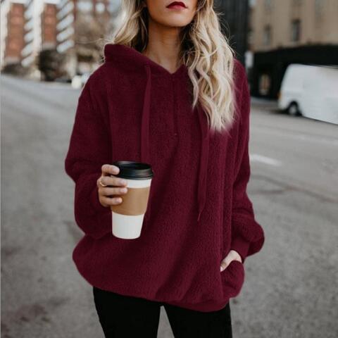 a woman in a red hoodie holding a cup of coffee