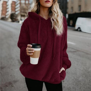 a woman in a red hoodie holding a cup of coffee