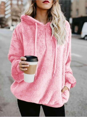 a woman in a pink hoodie holding a cup of coffee