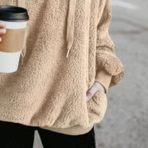 a woman holding a cup of coffee and wearing a sweater