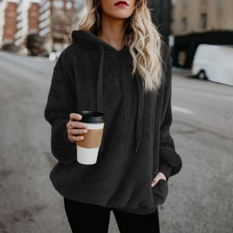 a woman in a black hoodie holding a cup of coffee