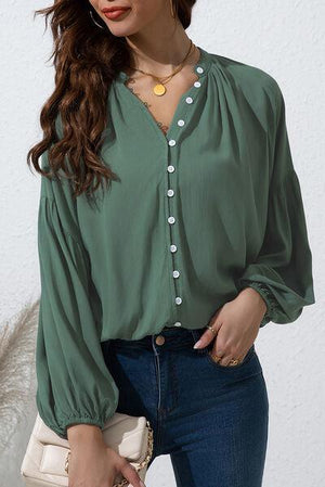 a woman wearing a green blouse and jeans