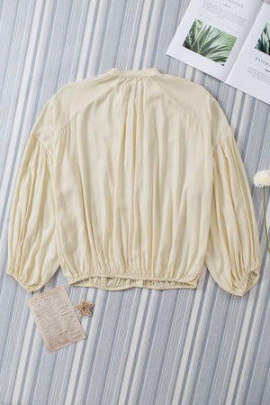 a white blouse sitting on top of a bed next to a book