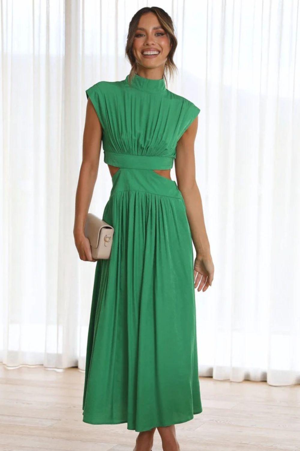 a woman in a green dress standing in front of a window