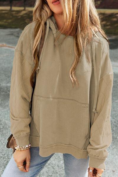 a woman with long hair wearing a tan hoodie