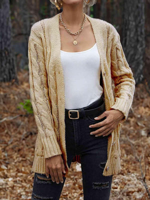 a woman standing in the woods wearing a cardigan