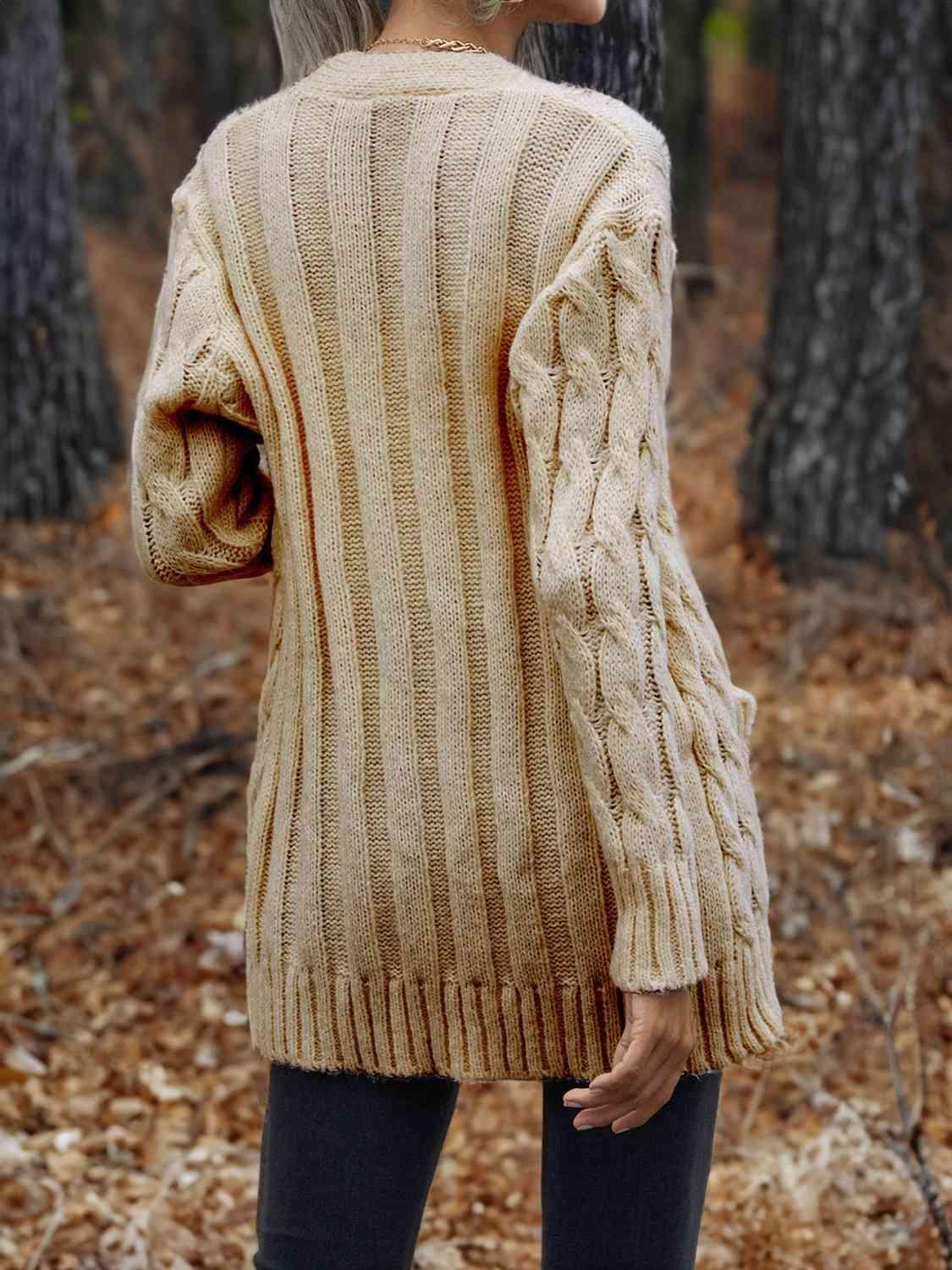 a woman standing in the woods wearing a sweater