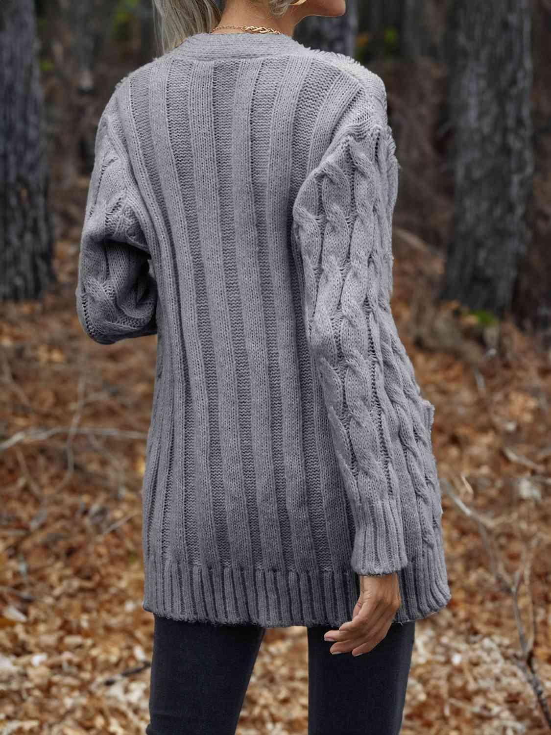 a woman wearing a gray sweater in the woods