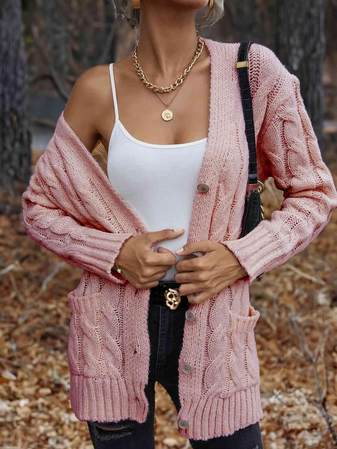 a woman wearing a pink cardigan and black pants