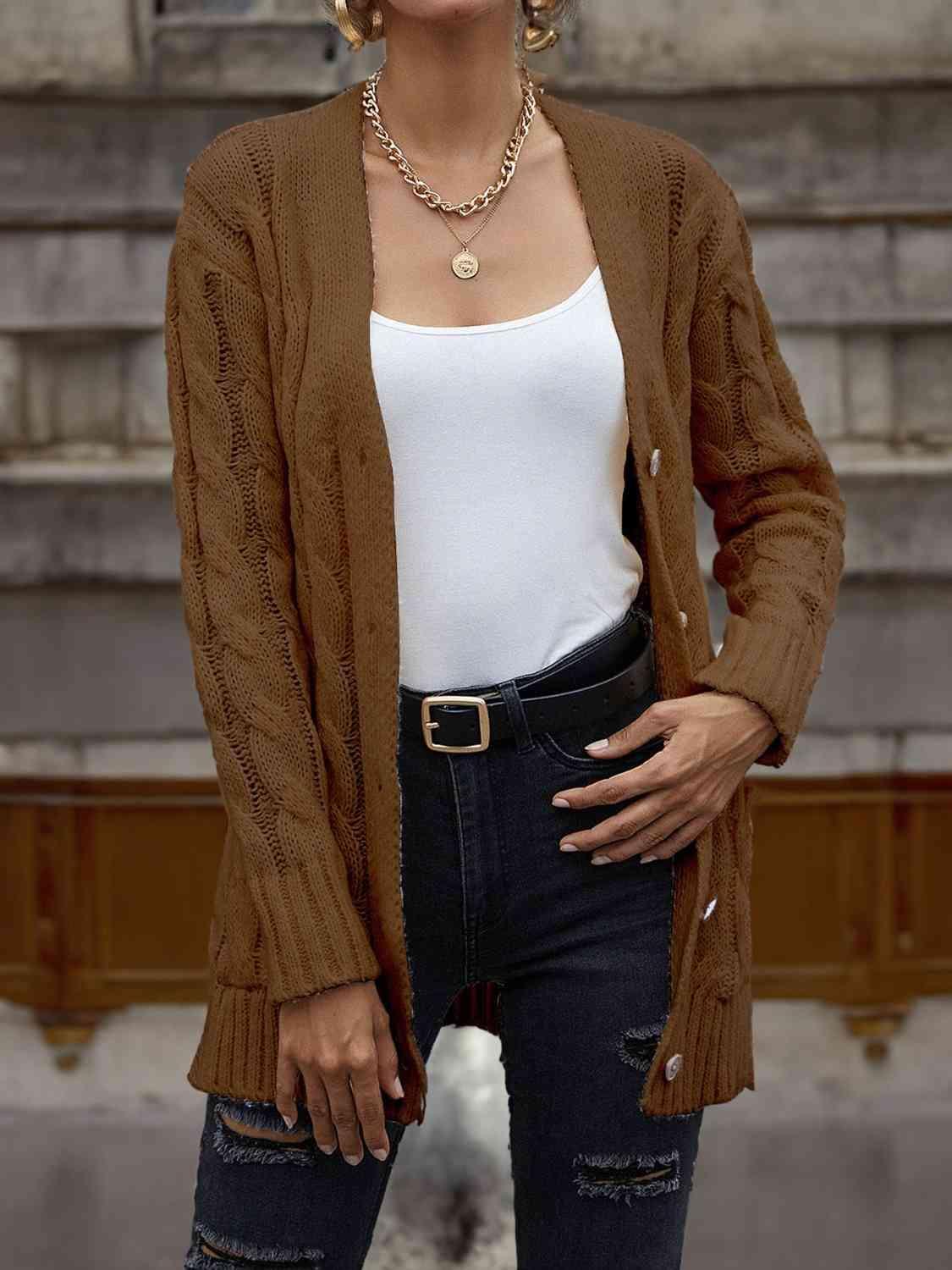 a woman standing in front of a building wearing a brown cardigan