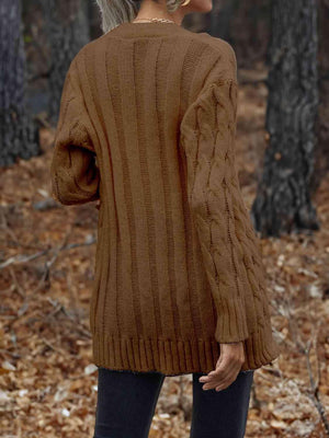 a woman standing in the woods wearing a brown sweater