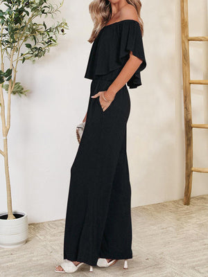 a woman wearing a black off the shoulder jumpsuit