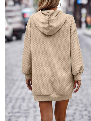 a woman walking down a street wearing a tan sweater dress