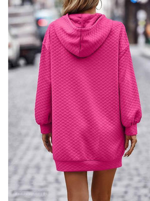 a woman in a pink sweater dress walking down a street