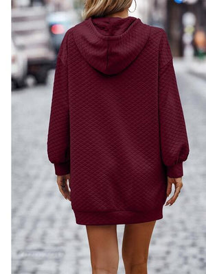 a woman walking down a street wearing a maroon sweater dress