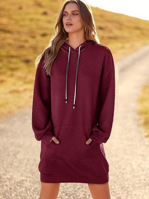 a woman standing on a road wearing a maroon sweater dress