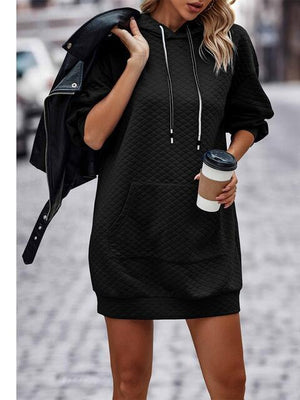 a woman in a black hoodie dress holding a cup of coffee