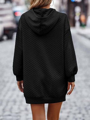 a woman walking down a street wearing a black hoodie