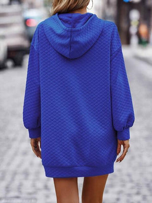 a woman walking down a street wearing a blue sweater dress