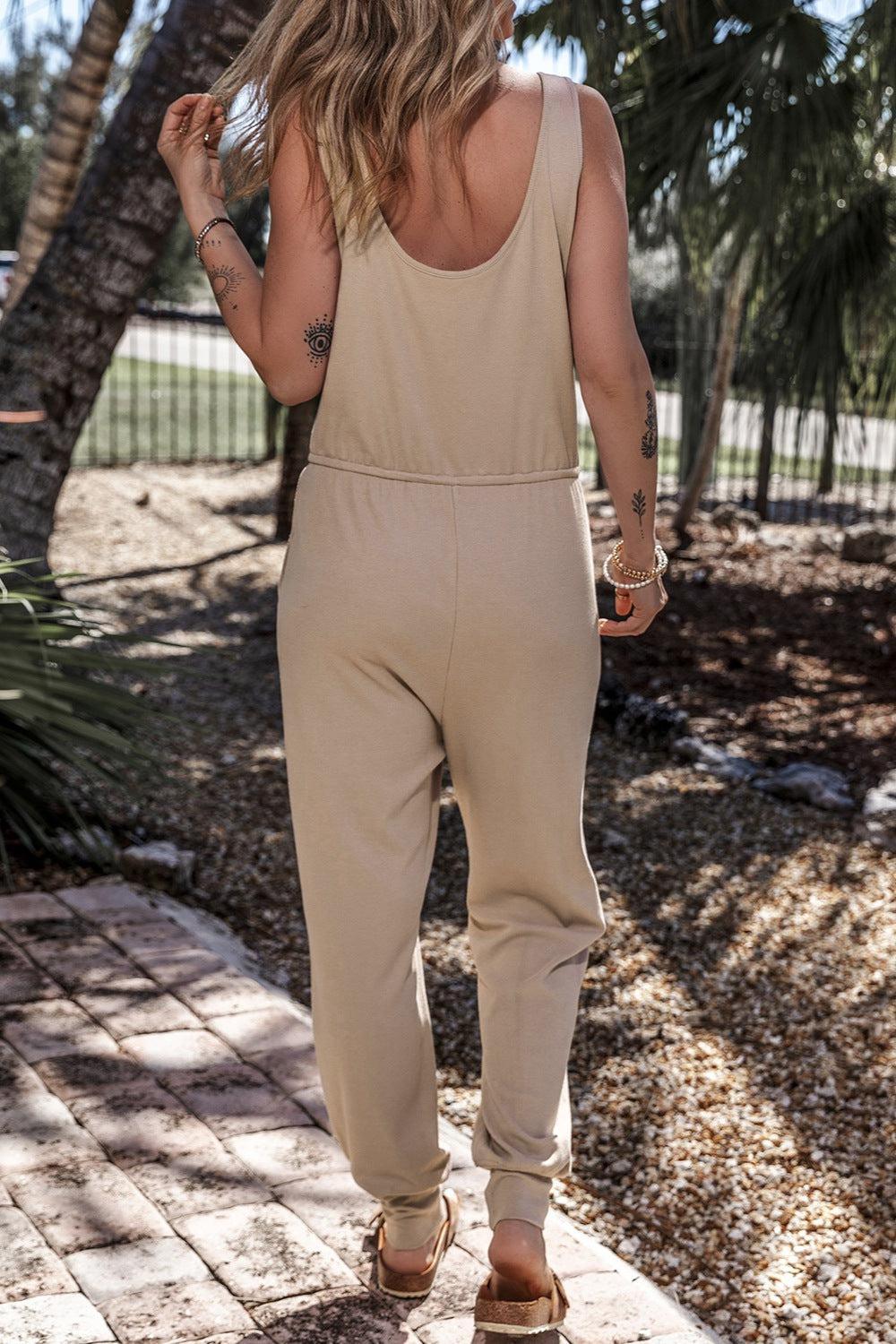 a woman walking down a sidewalk wearing a tan jumpsuit