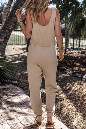 a woman walking down a sidewalk wearing a tan jumpsuit