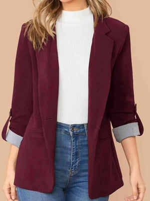 a woman wearing a burgundy blazer and jeans