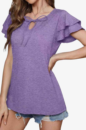 a woman wearing a purple top with a cut out shoulder
