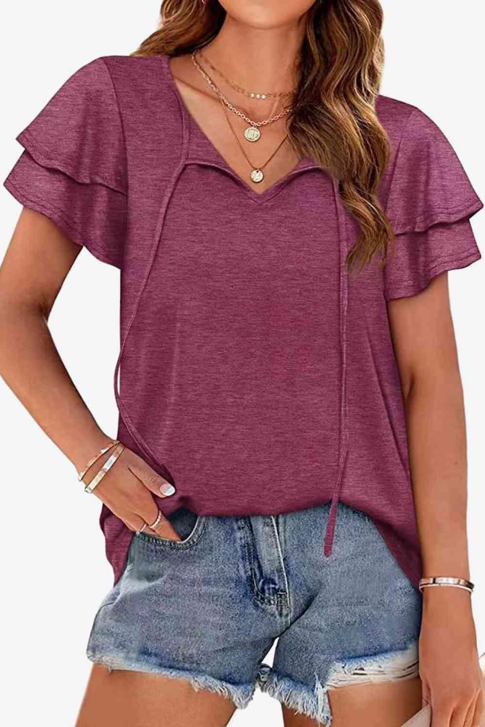 a woman wearing a purple top and denim shorts