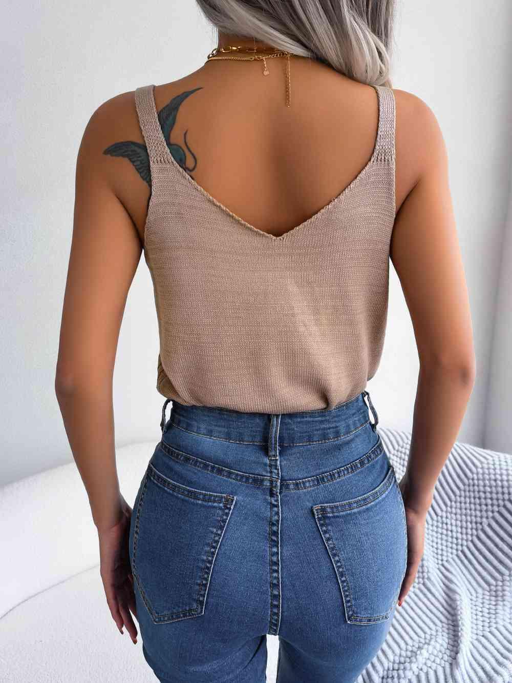 a woman with grey hair wearing jeans and a tank top