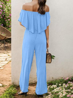 a woman in a blue jumpsuit standing next to a white wall