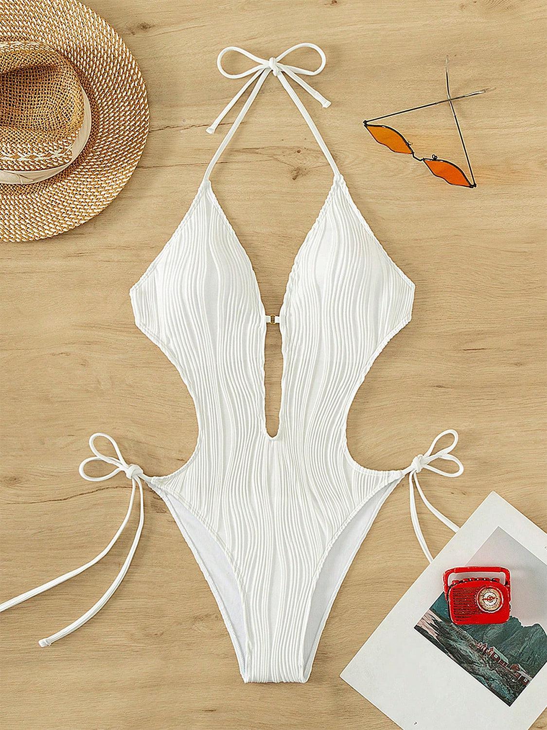 a white one piece swimsuit on a wooden table