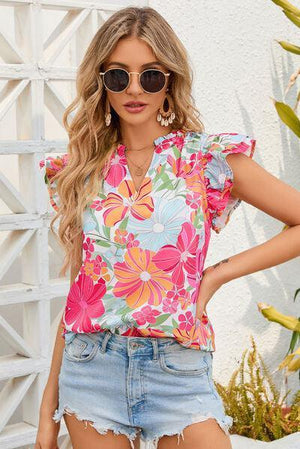 a woman wearing a floral top and denim shorts