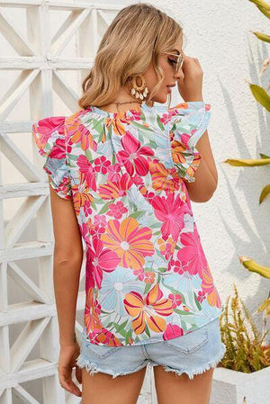 a woman wearing a floral top and denim shorts