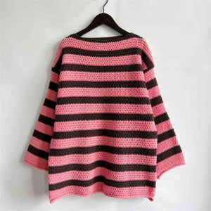 a pink and black striped sweater hanging on a wall