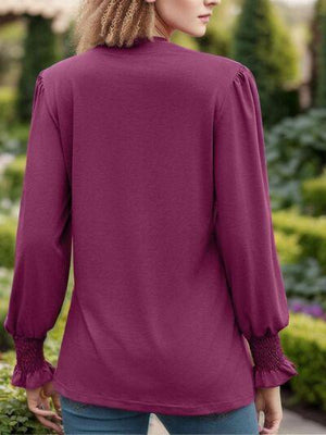 a woman wearing a purple blouse and jeans