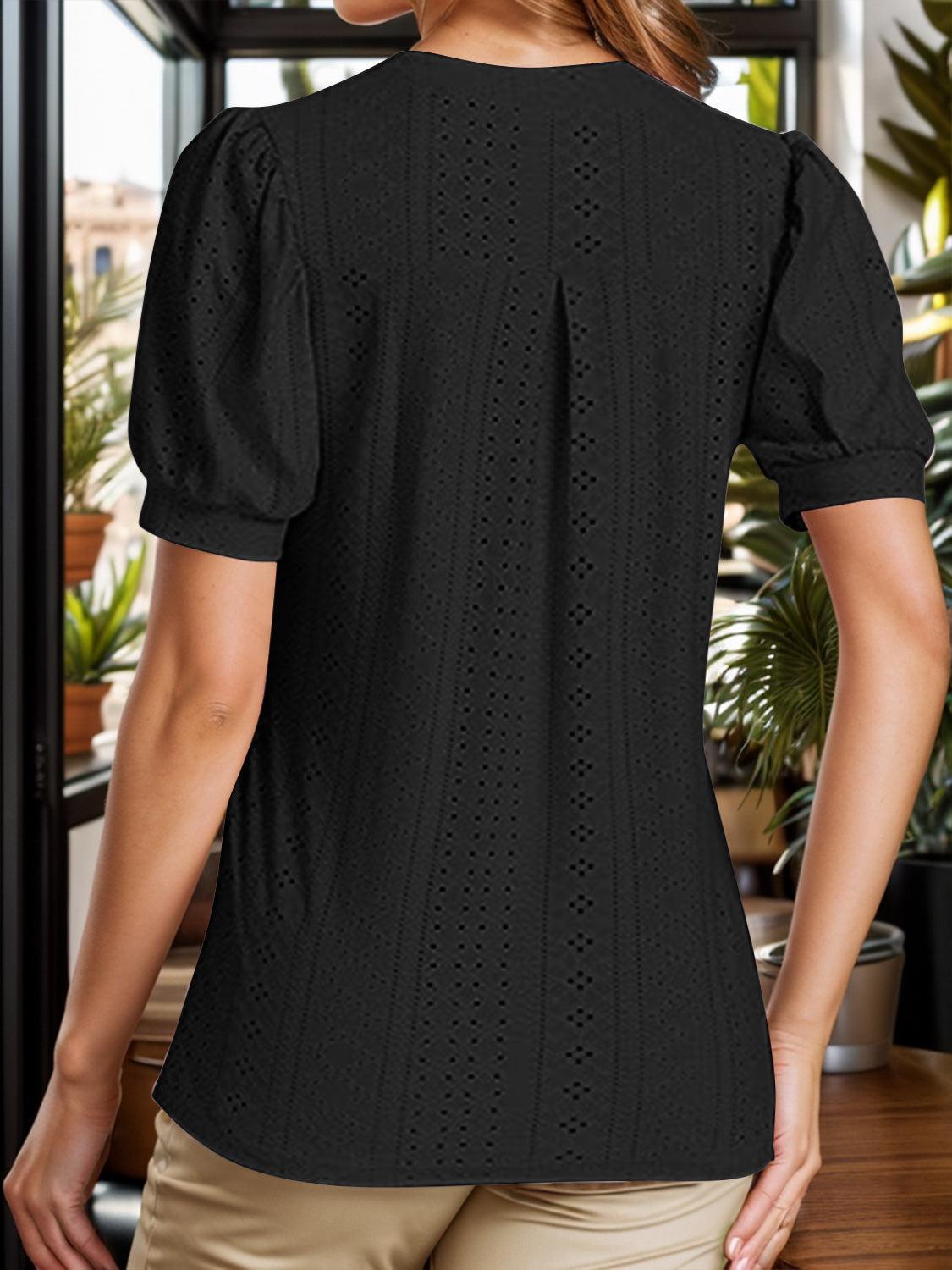 a woman standing in front of a window wearing a black top